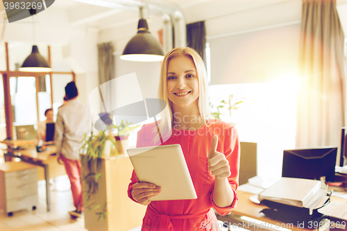 Image of woman with tablet pc showing thumbs up at office