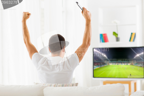 Image of happy man watching football or soccer game on tv