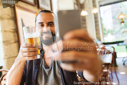 Image of man with smartphone drinking beer at bar or pub