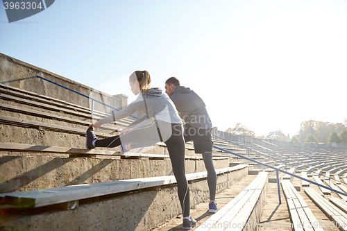 Image of couple stretching leg on stands of stadium