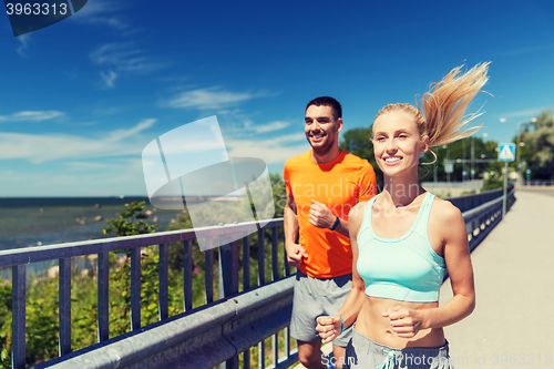 Image of smiling couple running at summer seaside