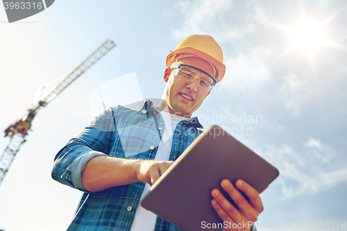 Image of builder in hardhat with tablet pc at construction