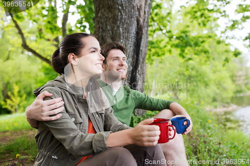 Image of happy couple with cups drinking in nature