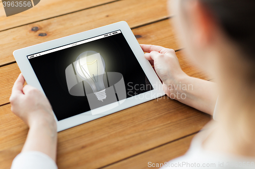 Image of close up of woman with tablet pc on wooden table