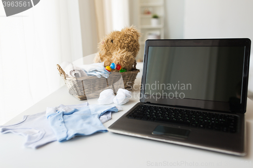 Image of close up of baby clothes, toys and laptop at home