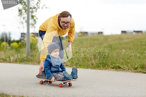 Image of happy father and little son riding on skateboard