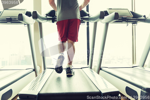 Image of close up of male legs running on treadmill in gym