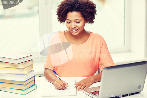 Image of happy african american woman with laptop at home