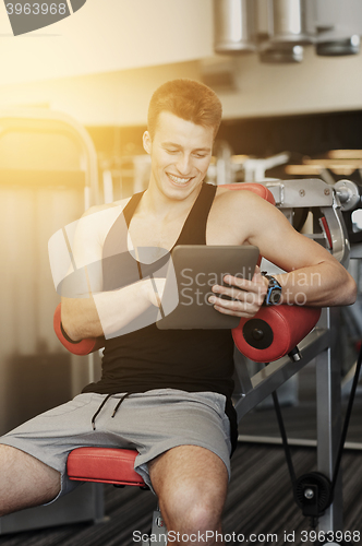 Image of smiling young man with tablet pc computer in gym