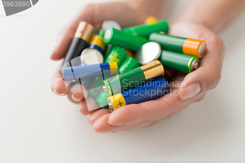 Image of close up of hands holding alkaline batteries heap