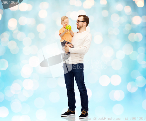 Image of happy father and little son with green apple