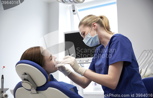 Image of female dentist checking patient girl teeth