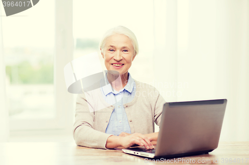 Image of happy senior woman with laptop at home