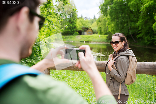 Image of couple with backpacks taking picture by smartphone