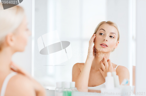 Image of happy young woman looking to mirror at bathroom