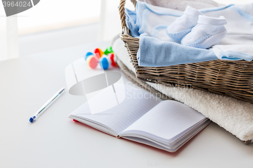 Image of close up of baby clothes for newborn and notebook