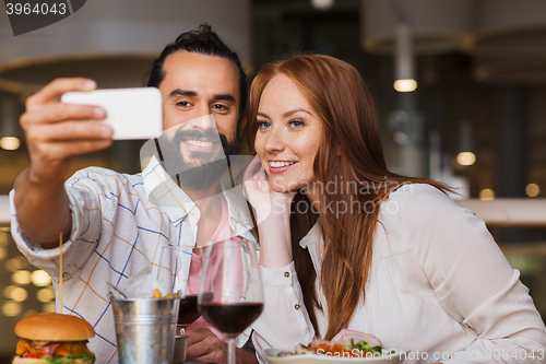 Image of couple taking selfie by smartphone at restaurant