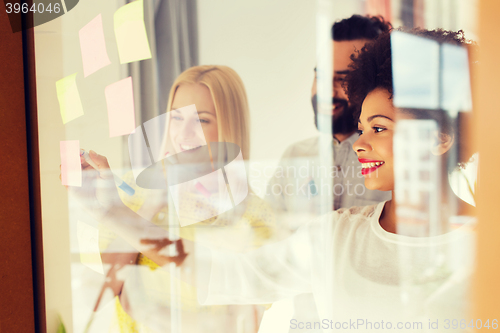 Image of happy creative team writing on stickers at office