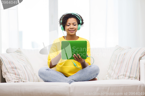 Image of happy african woman with tablet pc and headphones