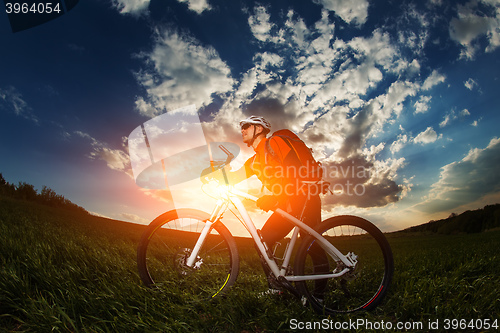 Image of biker in orange jersey riding on green summer field