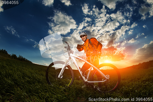 Image of Man Cyclist with bike on sunset