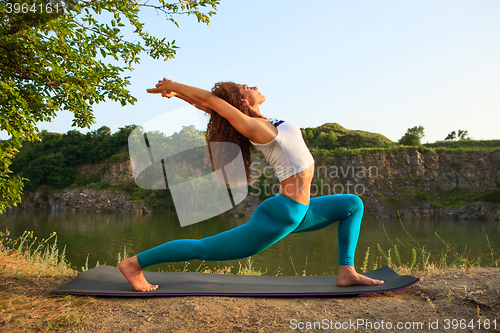 Image of Young woman is practicing yoga near river