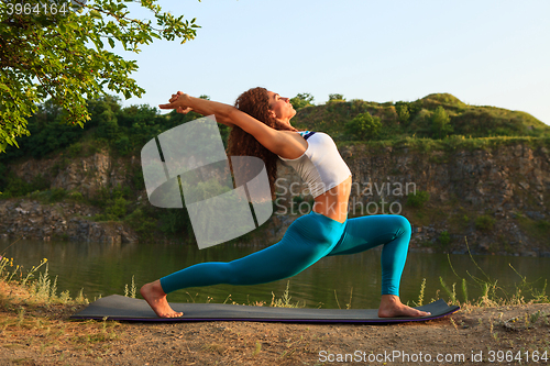 Image of Young woman is practicing yoga near river