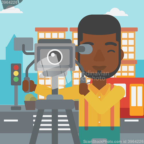 Image of Cameraman with movie camera on a tripod.