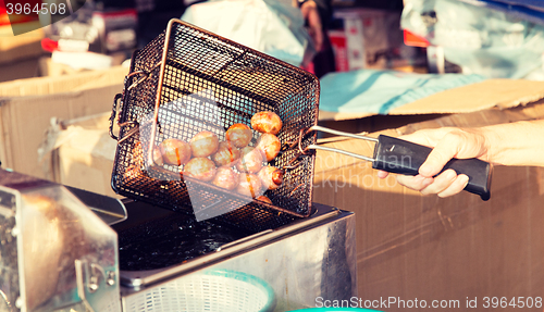 Image of close up of cook frying meatballs at street market