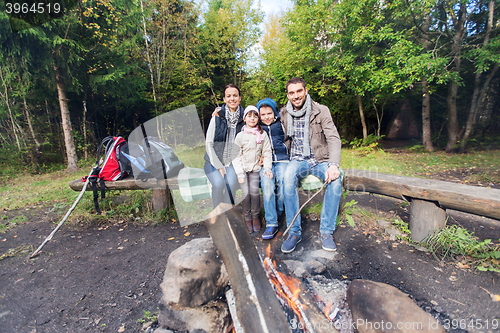 Image of happy family sitting on bench at camp fire