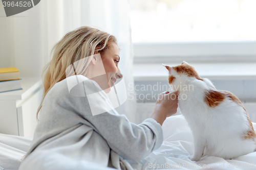 Image of happy young woman with cat in bed at home