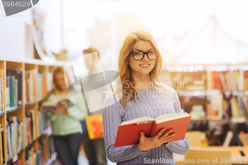 Image of happy student girl or woman with book in library