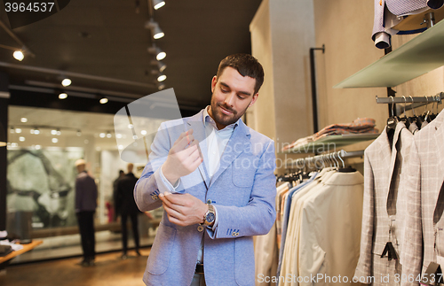 Image of happy young man trying jacket on in clothing store