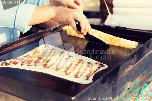 Image of close up of cook frying pancakes at street market