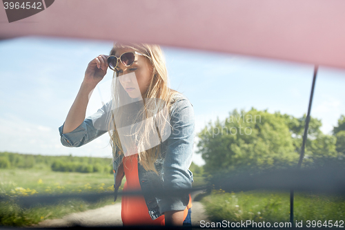 Image of woman with open hood of broken car at countryside