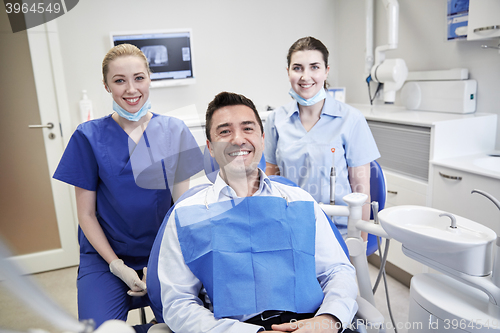 Image of happy female dentists with man patient at clinic