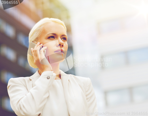 Image of serious businesswoman with smartphone outdoors