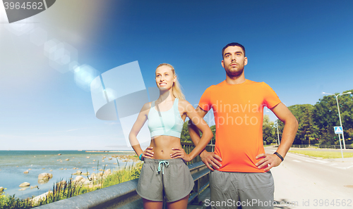 Image of happy couple exercising at summer seaside