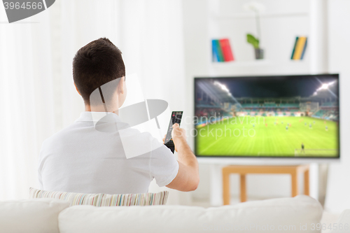 Image of man watching football or soccer game on tv at home