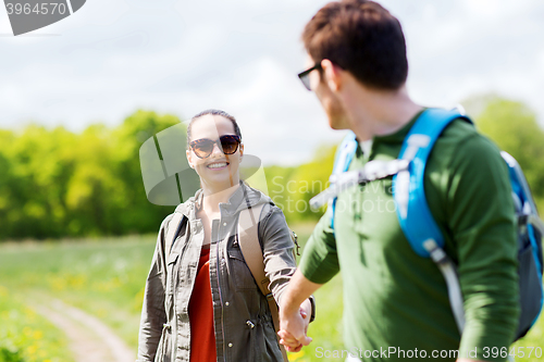 Image of happy couple with backpacks hiking outdoors