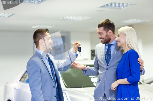 Image of happy couple with car dealer in auto show or salon