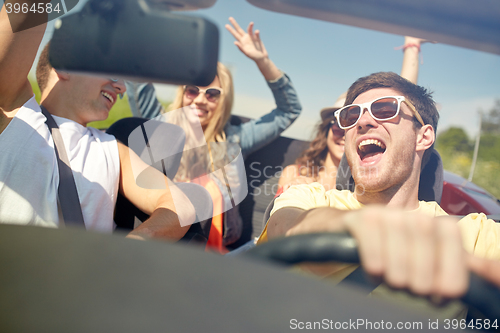 Image of happy friends driving in cabriolet car