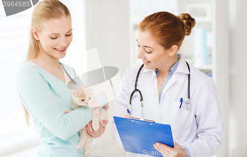 Image of happy woman with cat and doctor at vet clinic