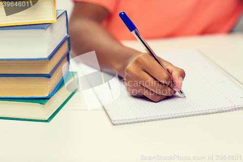 Image of close up of african woman hand writing to notebook