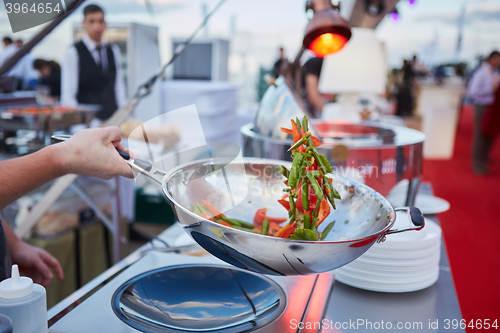 Image of chef tossing vegetables in a wok