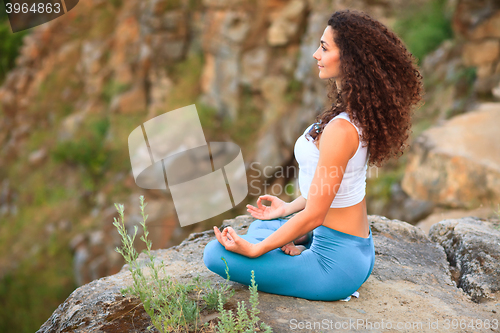 Image of Young woman is practicing yoga near river