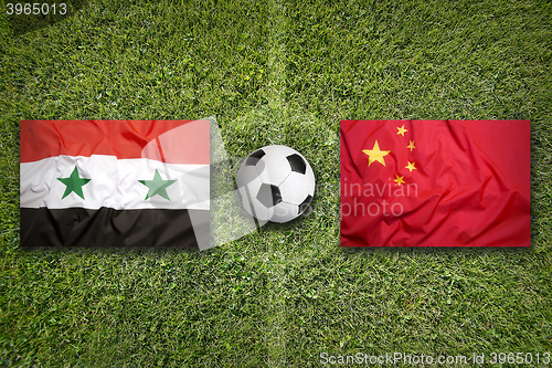 Image of Syria vs. China flags on soccer field