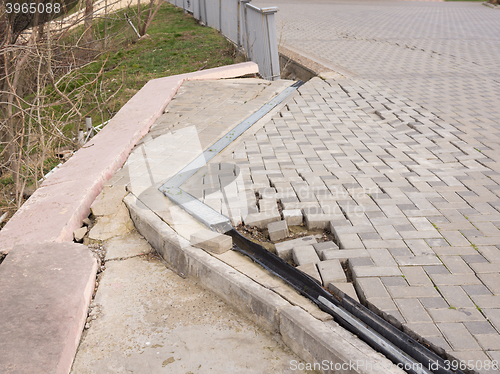 Image of The destruction of the pedestrian walkway of pavers fixed concrete screed, as well as the breaking behavior of the fence