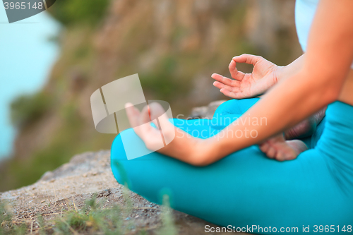 Image of Young woman is practicing yoga near river