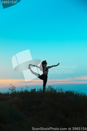 Image of The silhouette of young woman is practicing yoga